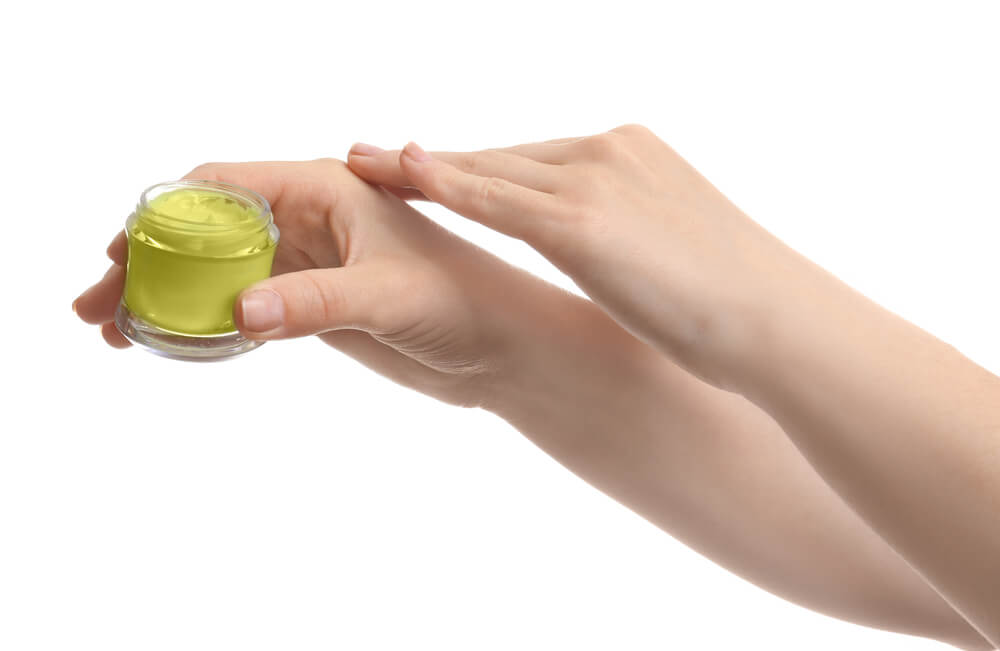 Hands of woman applying hemp lotion onto skin